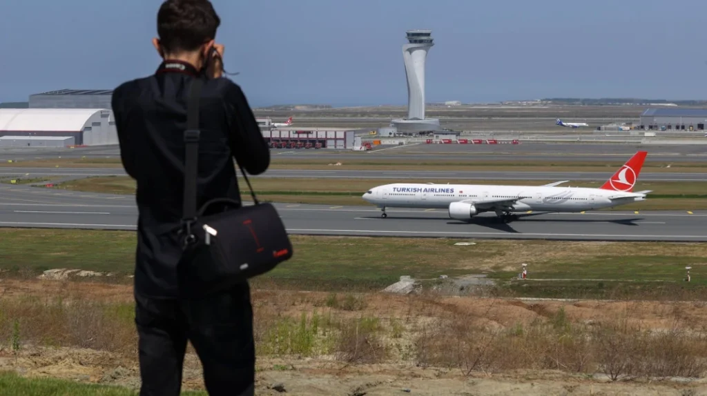 A imagem mostra um spotter fotografando a chegada de um 777 no aeroporto de Istanbul, na Turquia. Plane spotting em ação