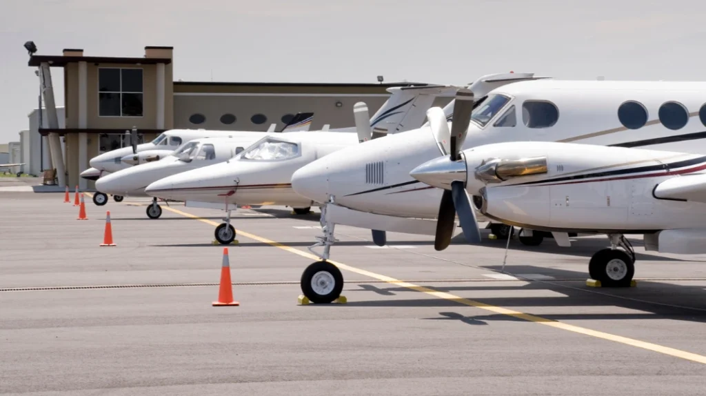 A imagem mostra algumas aeronaves executivas pequenas destinadas a fretamento, estacionadas próximo à pista do aeroporto